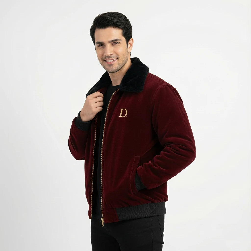 Angled front view of men's maroon velvet winter jacket with black faux fur collar, with the model holding the collar and smiling.