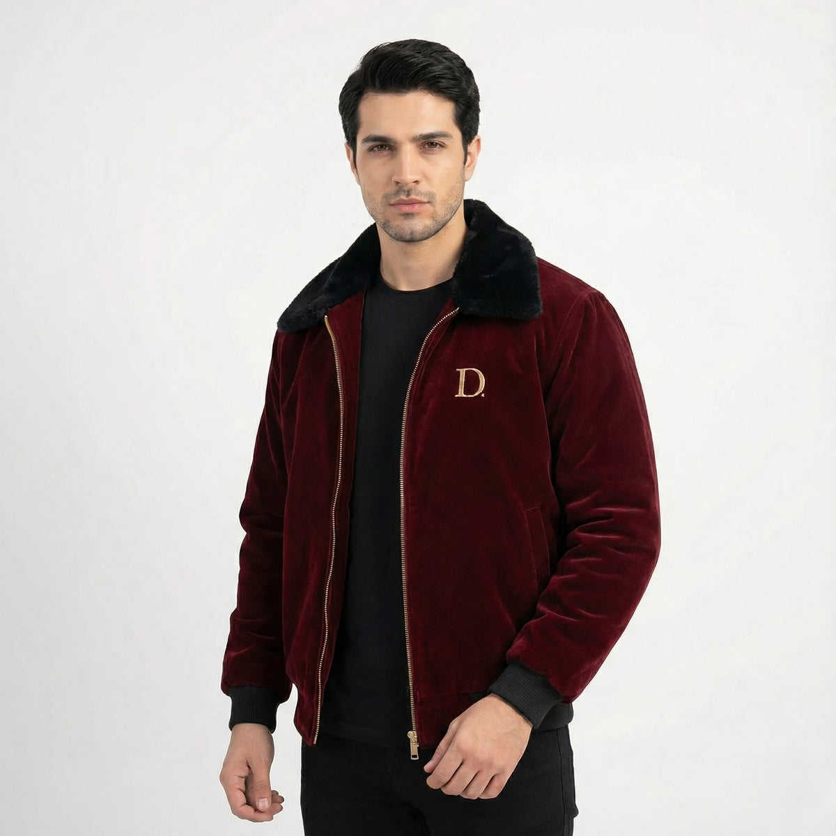 Front view of men's maroon velvet winter jacket featuring a black faux fur collar and gold "D" embroidery, worn over a black t-shirt.