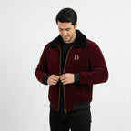 Front view of men's maroon velvet winter jacket with black faux fur collar, with model looking down and adjusting the zipper.
