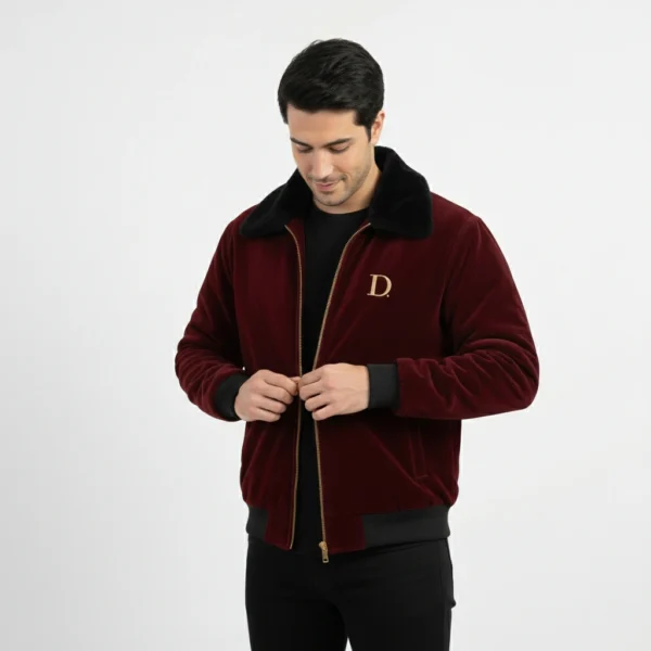 Front view of men's maroon velvet winter jacket with black faux fur collar, with model looking down and adjusting the zipper.